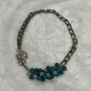 Silver tone necklace with turquoise and white stone cluster.